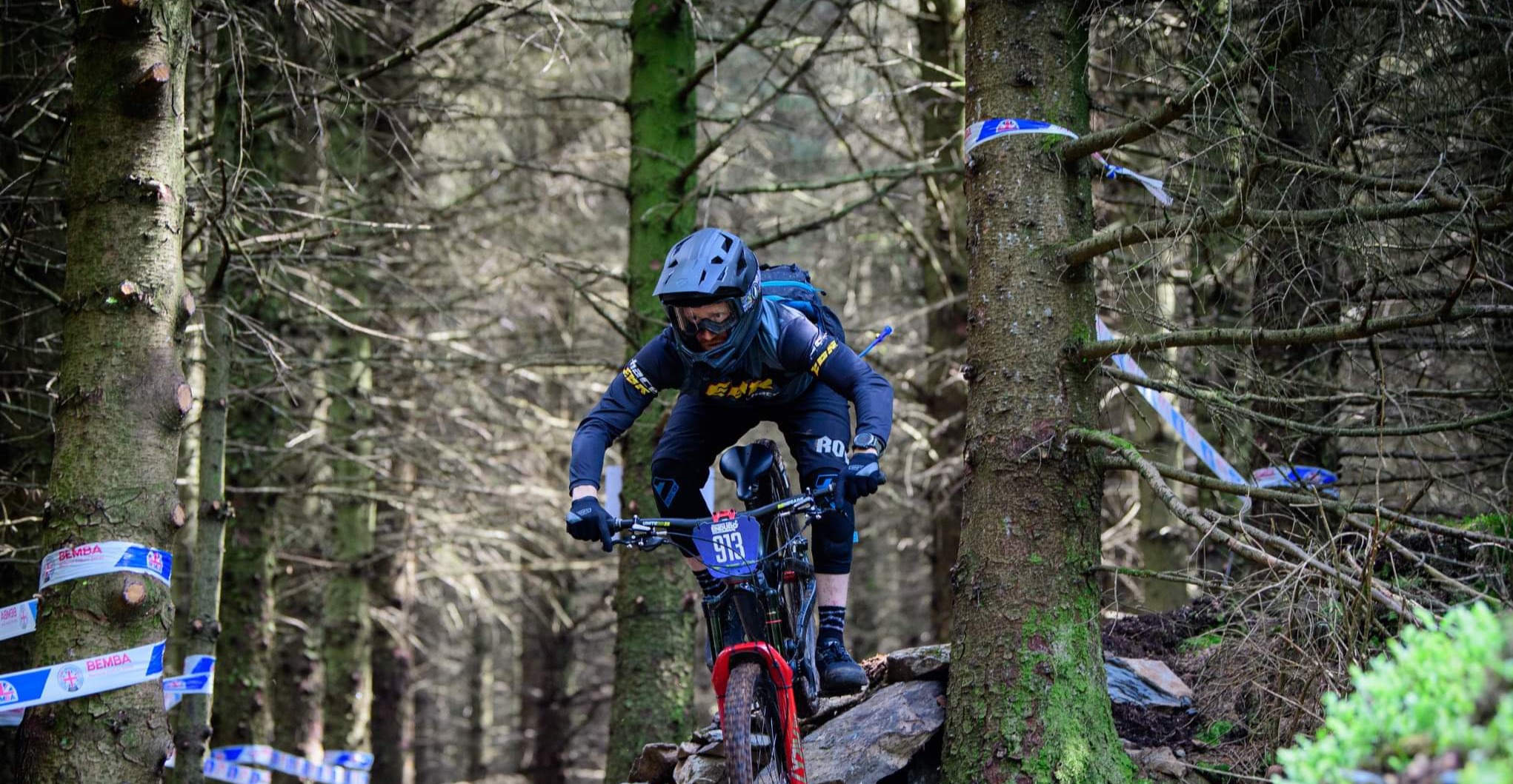 A Team EBR rider racing through a forest on a mountain bike
